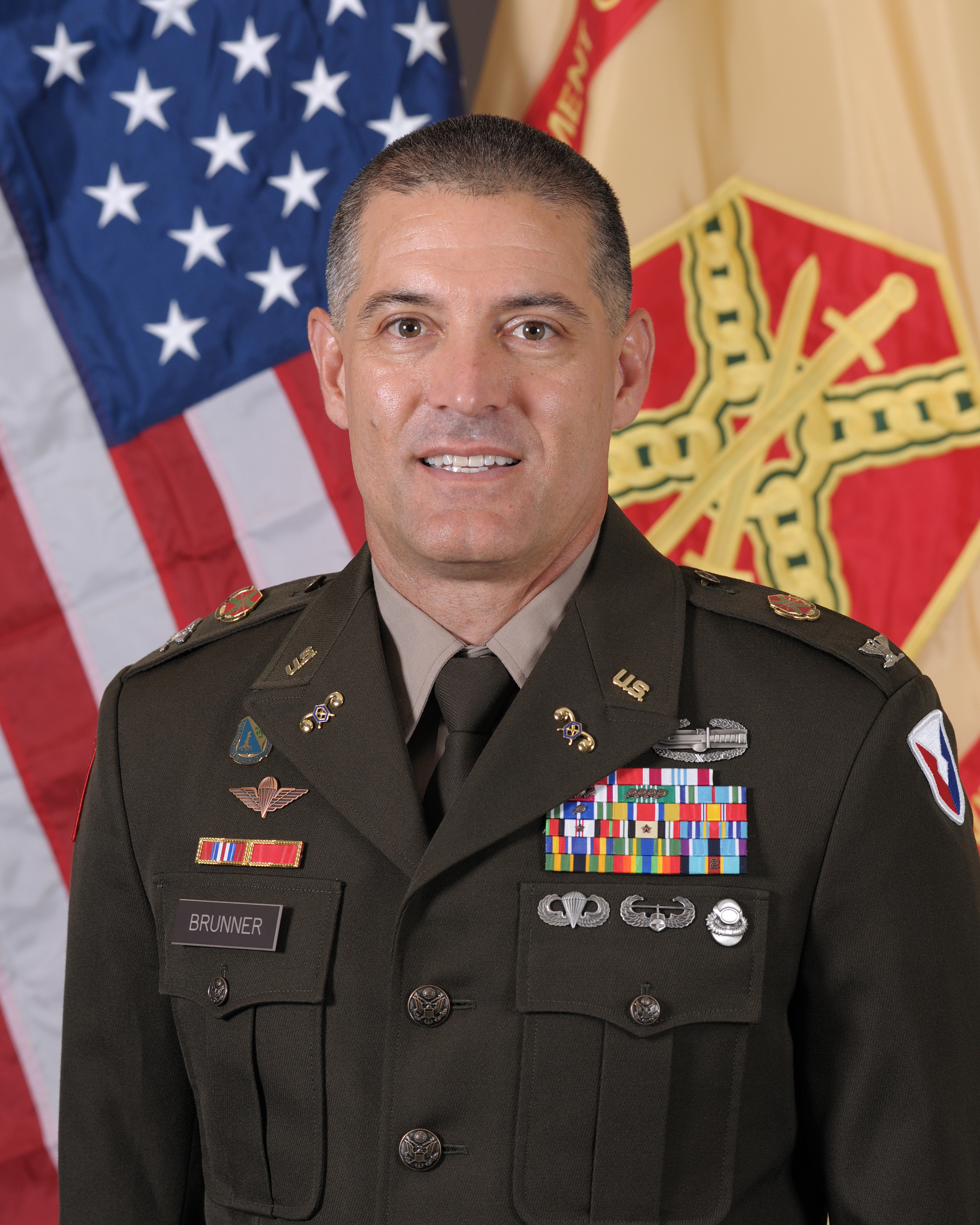 Photo of Colonel Vance Brunner in uniform in front of U.S.and IMCOM flags.