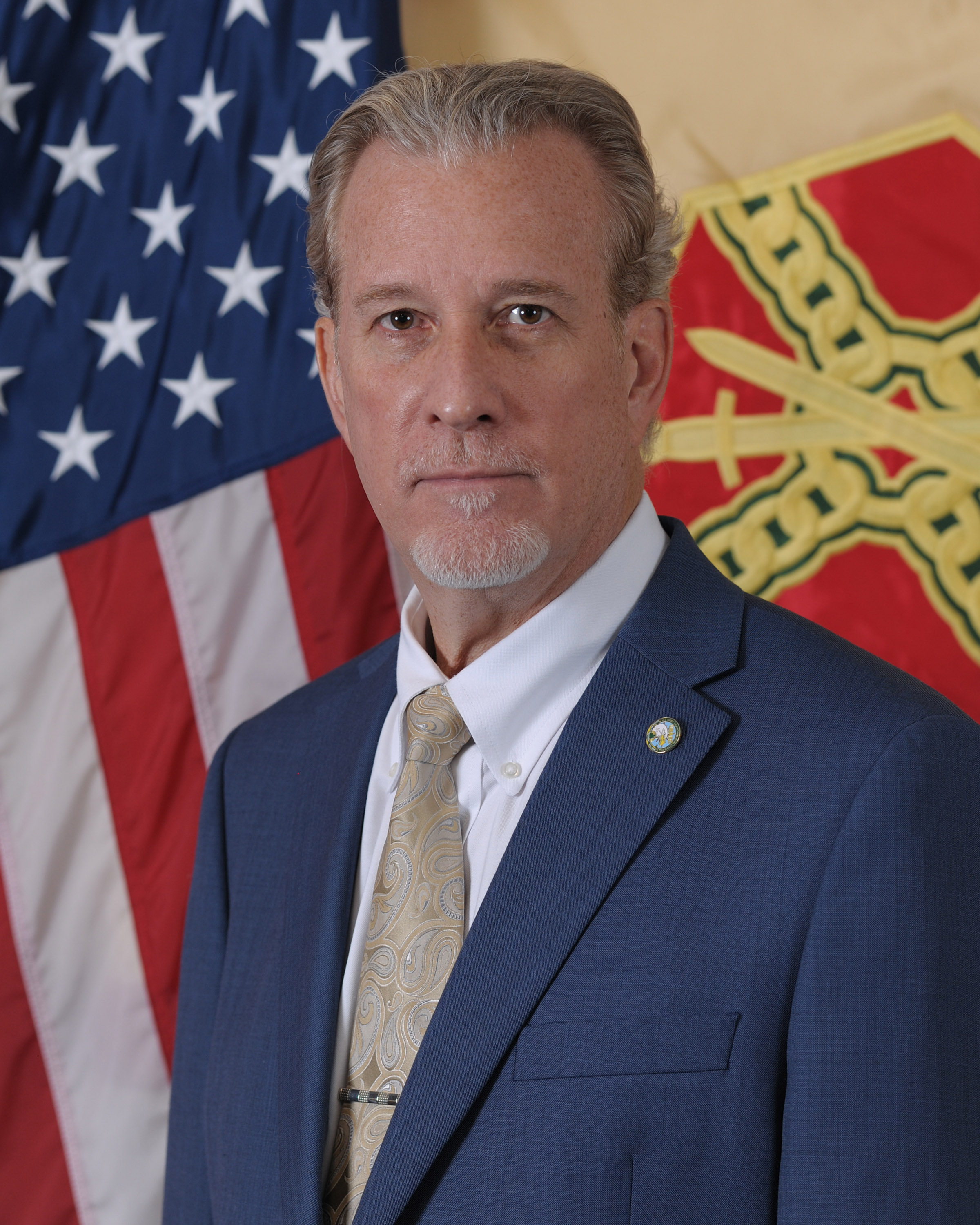 Photo of Mr. Joel Godfrey in a suit and tie standing in front of the U.S. and IMCOM flags.